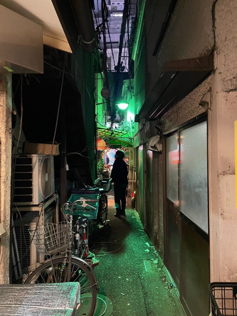 会社メディアの街のイメージとして使う、緑の灯りが差す路地の提供写真